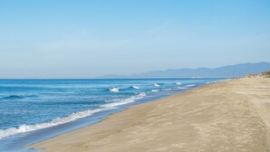 A beach with a clear sky, calm sea, and distant mountains. - Cabane Container Hotel - Adults Only (Puerto Escondido)