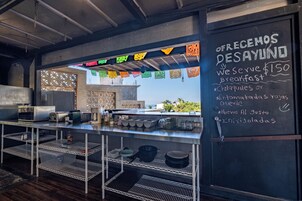 A breakfast counter with a chalkboard menu, kitchen equipment, and a decorative ceiling.