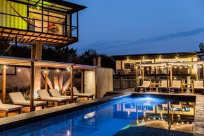 Un hotel moderno con piscina, sillas de descanso y zona de bar.