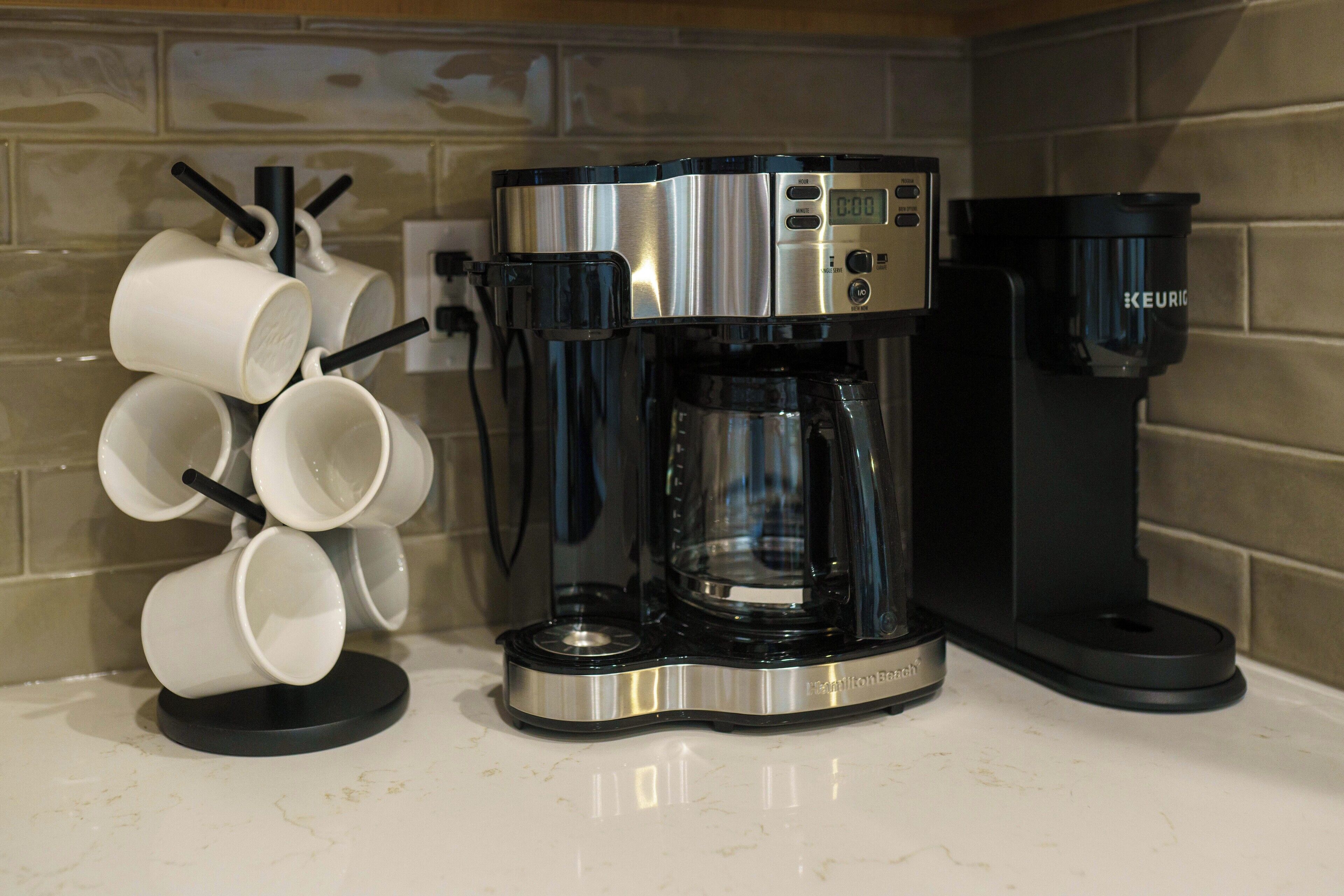 Une machine à café dotée d’un écran numérique, d’un porte-tasse et d’un distributeur de dosettes de café Keurig, posée sur un plan de travail de cuisine.