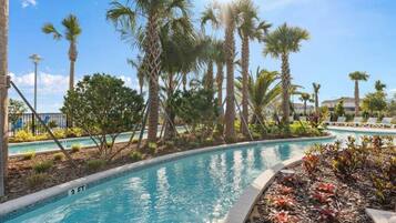 A pool area with palm trees, lounge chairs, and a clear blue sky.