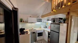 A compact kitchen with white cabinets, a stainless steel refrigerator, and a patterned floor. - Tiny house with nordic Bath, (Criel-sur-Mer)
