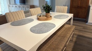 A dining table with woven placemats, striped chairs, and a wooden centerpiece.