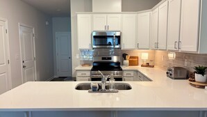 A modern kitchen with white cabinetry, stainless steel appliances, and a central island with a sink.