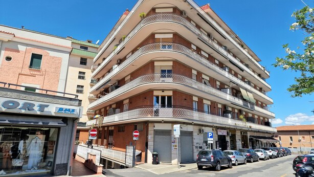 A multi-story building with balconies, a storefront with a sign, and parked cars. - Vacation House Fiore Ciampino Airport - Rome Station (Ciampino)