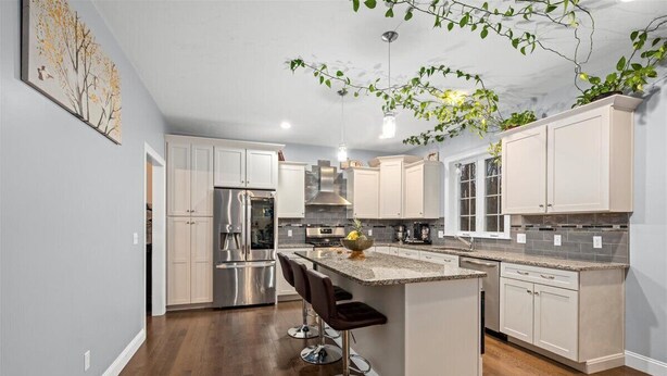 A modern kitchen with white cabinets, stainless steel appliances, and a central island with bar stools.