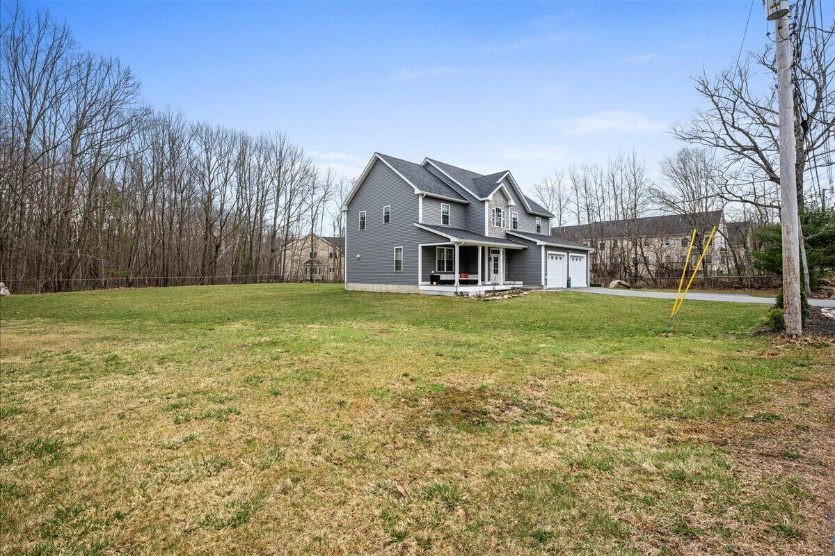 A two-story house with a large front porch, a garage, and a well-maintained lawn.