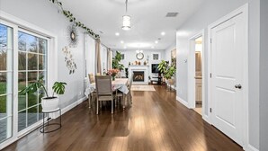 A spacious room with hardwood flooring, a dining area with a table and chairs, a fireplace, and a television.
