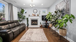 A living room with a fireplace, leather sofa, and potted plants.