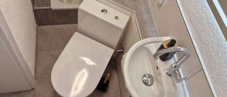 Un baño con inodoro, bidé y lavamanos.