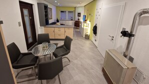 Een compacte leefruimte met een eethoek, kitchenette en een kleine badkamer.