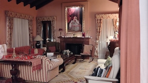 Una sala acogedora con chimenea, un sofá a rayas y un cuadro grande encima.