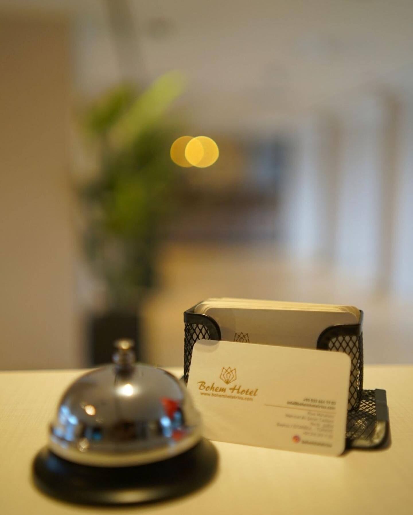 Zona de recepción de un hotel, con un timbre, un portatarjetas con una tarjeta y un fondo desenfocado.