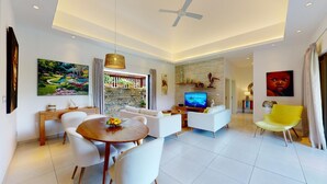 Una sala de estar moderna con comedor, televisor y una silla de color amarillo brillante.