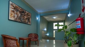 A hallway with a fire extinguisher, two wooden chairs, a large abstract painting, and a potted plant. - A Charming Retreat in Lubumbashi (Lubumbashi)