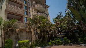 A multi-story hotel with balconies, a fountain, and tropical landscaping. - A Charming Retreat in Lubumbashi (Lubumbashi)