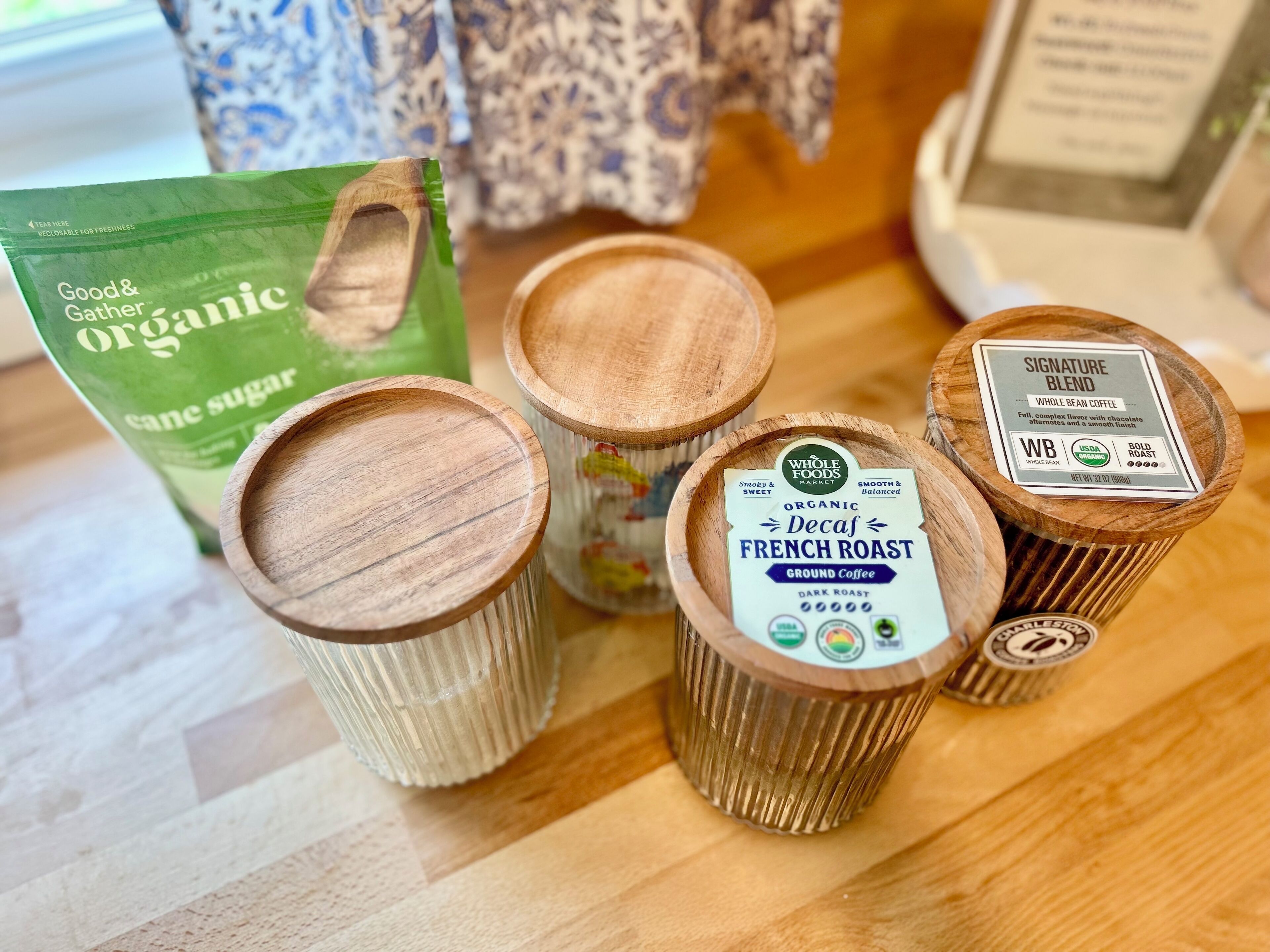 Una mesa de madera con recipientes de café y un paquete de azúcar de caña orgánica.