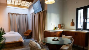 A hotel room with a bed, a dining table with chairs, a TV, and a kitchen area. - Ocean Park Beach Club Full (San Juan)