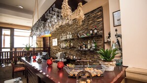 Eine Bar mit einer Holztheke, hängenden Weingläsern und Flaschenregalen.