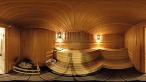 Eine Sauna mit Holzwänden und Bänken, eine kleine Bank mit Handtuch sowie eine Bank mit Handtuch und einem kleinen Behälter.