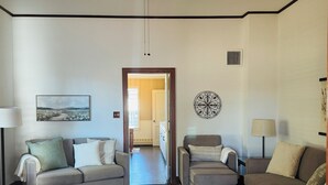 Una sala de estar con dos sofás, un tapete estampado, un adorno en la pared y una puerta que da a otra habitación.