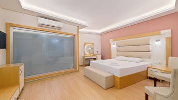 A modern hotel room with a large bed, bedside table, and a built-in bench.