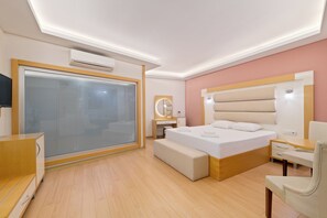 A modern hotel room with a large bed, bedside table, and a built-in bench. - HAN URLA OTEL (Urla)
