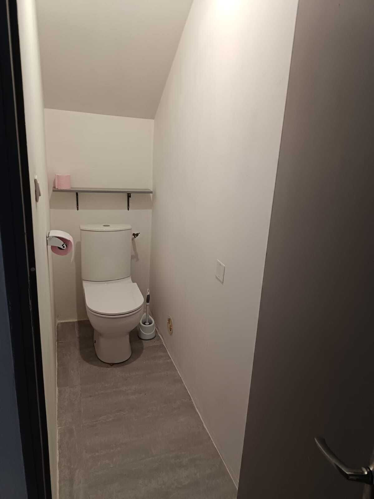 A small, clean bathroom with a toilet, a toilet paper holder, and a bidet.