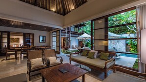 Un vestíbulo amplio con techo alto, ventanas grandes y una zona de estar con sofá y sillones.