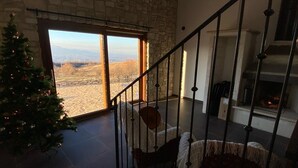 Una escalera conduce a un segundo piso con un muro de piedra y un ventanal grande.