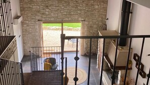 Un espacio amplio con chimenea de piedra, una escalera y vistas a un área exterior.