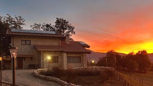 Un edificio de piedra con techo de tejas, camino de entrada pavimentado y pared de piedra con cerramiento.
