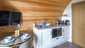A compact kitchen with wooden ceiling, white cabinets, a microwave, and a sink.