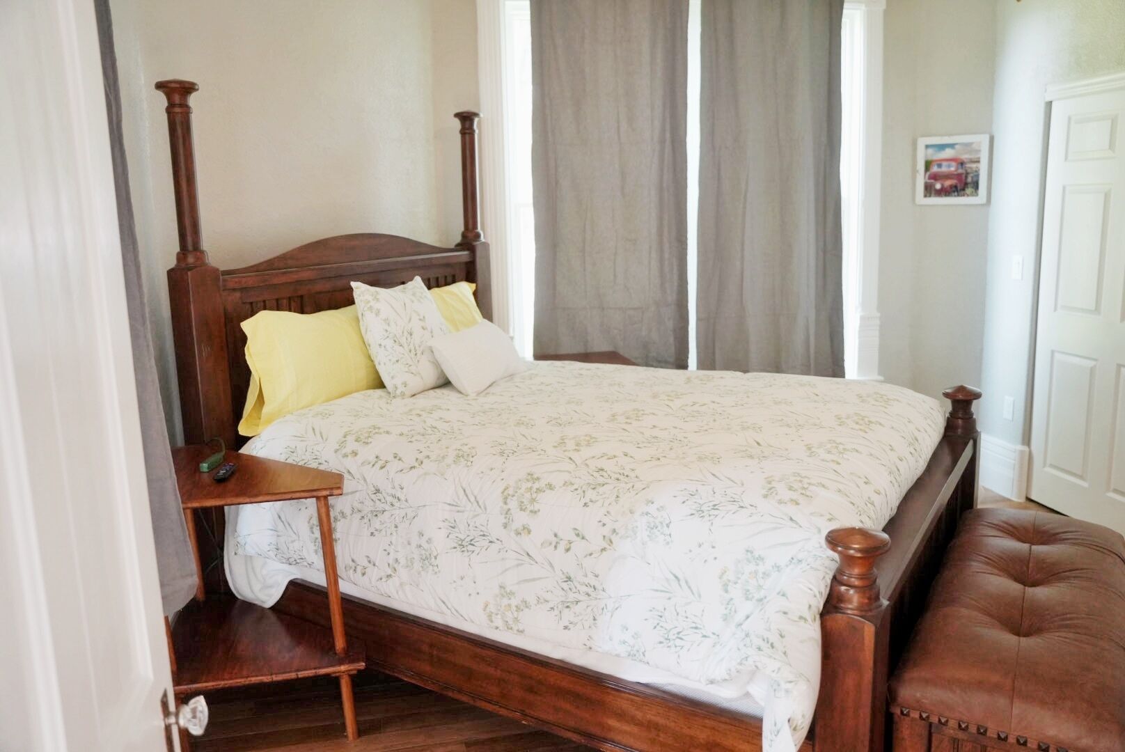 A bedroom with a wooden four-poster bed, a bedside table, and a bench.