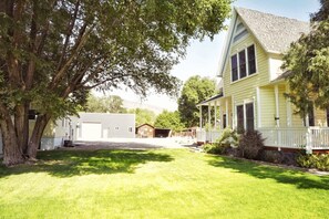 A two-story house with a porch, a garage, and a well-maintained lawn. - Relaxing Home W/HUGE Yard & Firepit! (Junction)