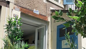 A small courtyard with a blue trampoline, wooden planter boxes with green plants, and a blue door. - "La Victoire" Fisherman's house at an alleyway from the sea... (Saint-Aubin-sur-Mer)