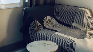 A corner room with a window, a sofa, and a small round table. - The Cozy Home (Nha Trang)