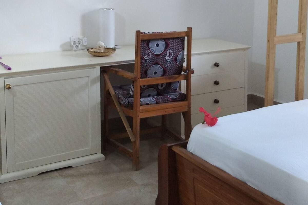 Un dormitorio con una cama de madera, un escritorio con silla, un radiador y un aire acondicionado instalado en la pared.