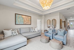 A modern living room with a sectional sofa, armchairs, a coffee table, and a large abstract painting.