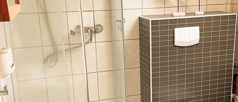 Une salle de bain avec une douche à parois de verre, un lavabo blanc et des toilettes.