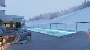 A modern outdoor pool area with a glass barrier, seating, and a view of a snowy hillside. - Apartment in Berwang With Ski-in/ski-out (Berwang)
