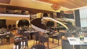 A spacious dining area with multiple tables set for a meal, a grand staircase, and a chandelier. - Hotel Boutique Gran Paradiso Resort (Campos do Jordão)