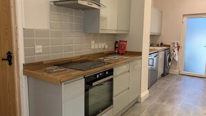 A modern kitchen with a built-in oven, a gas stove, and a stainless steel range hood. - Cozy barn conversion within minutes from Silverstone. (Towcester)
