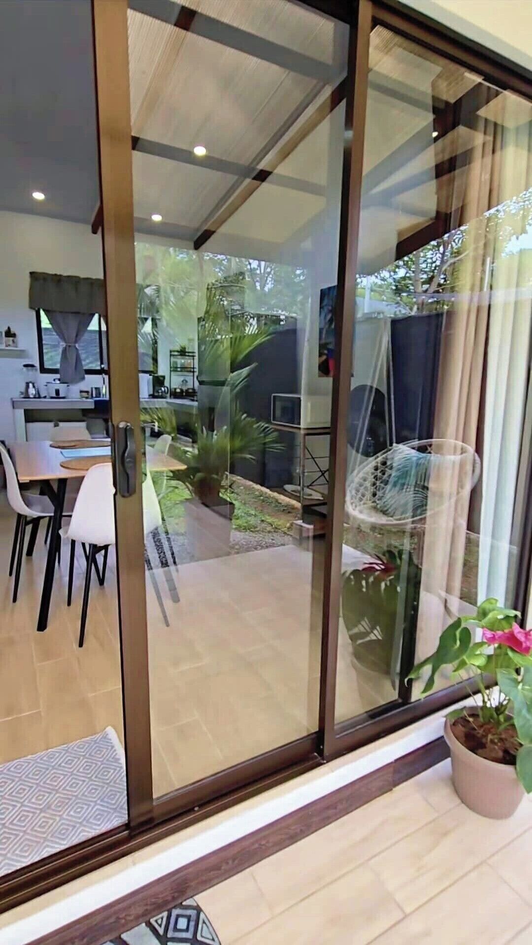 Una cocina moderna con comedor, una puerta corrediza de vidrio que da a un jardín y una planta en maceta.