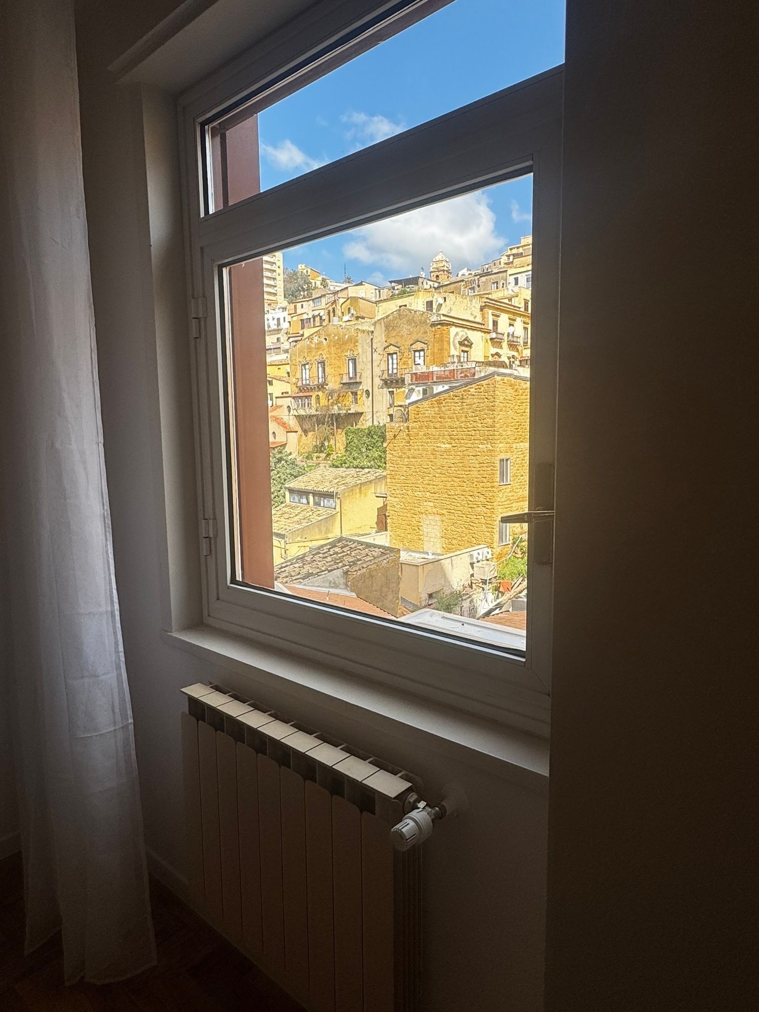 A window with a view of a densely packed urban area with traditional buildings.