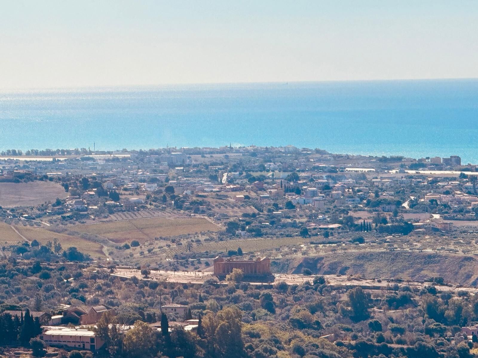 A coastal town with a mix of residential and commercial buildings, a prominent historical building, and a view of the sea.