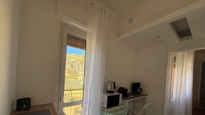 Une petite pièce lumineuse avec un balcon, un coin cuisine et une vue sur le paysage urbain.
