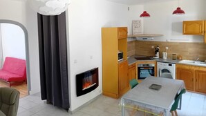 Una cocina moderna con horno empotrado, microondas y lavavajillas, un comedor con mesa y sillas, y una chimenea.