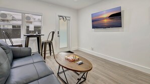 Una sala de estar moderna con un sofá de cuero, una mesa de centro de madera y un cuadro de un atardecer.