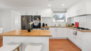 A modern kitchen with white cabinets, a wooden countertop, stainless steel appliances, and a window providing natural light. - Family house,3 Rooms,4Beds, 5 to 8 People,Pet-Friendly Big Yard lots of Parking (Duffy)